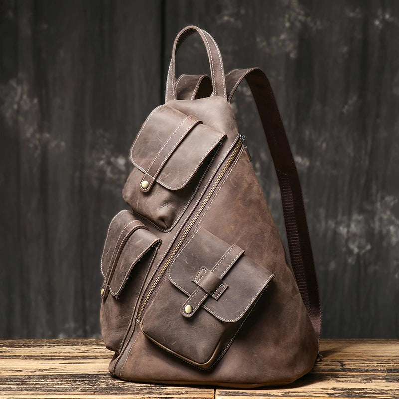 Dark brown men's leather backpack with exterior  pockets, diagonal zipper, and adjustable straps - front view.