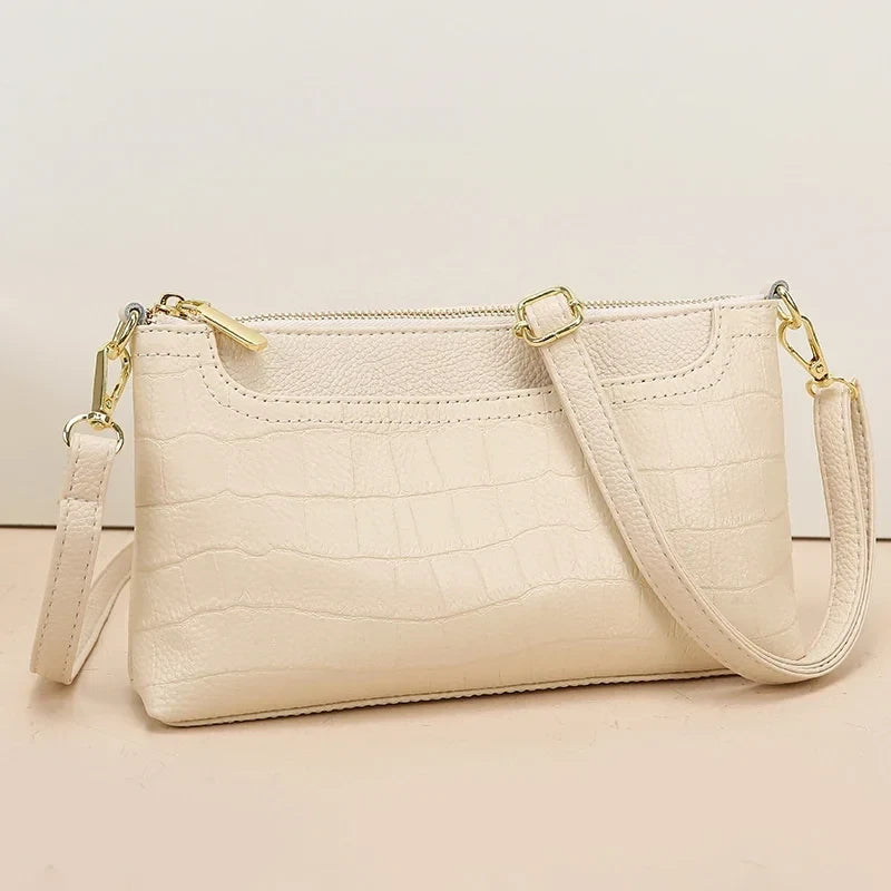 Beige crocodile leather bag with gold details, ideal for a sophisticated and elegant look. front view.