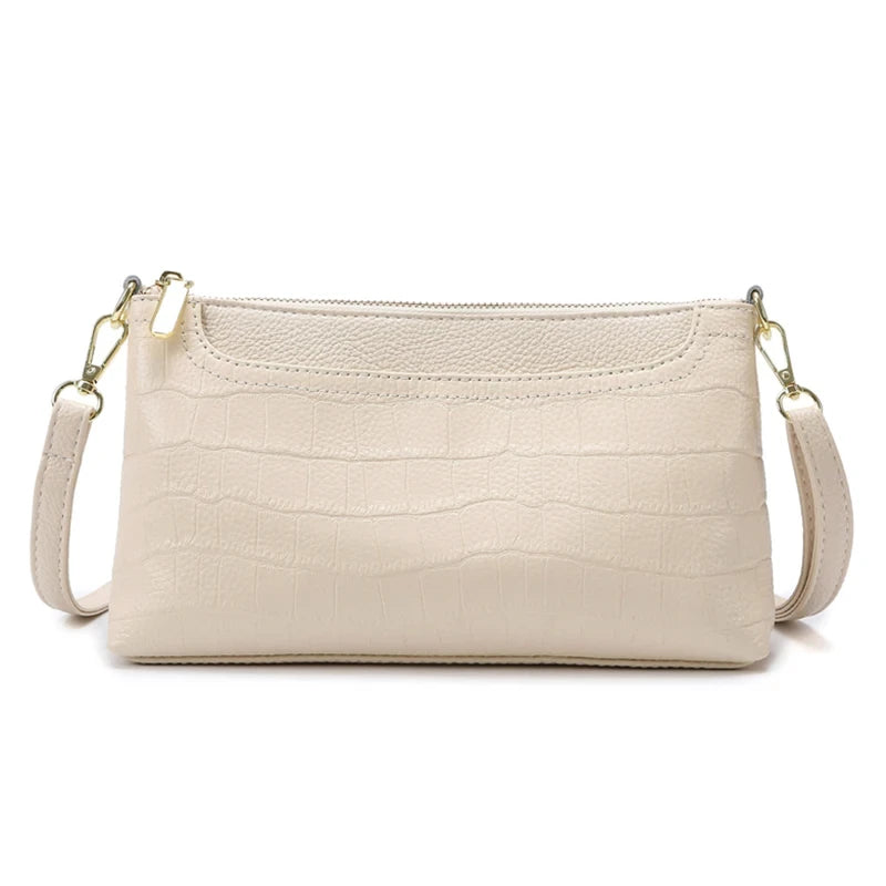 Beige leather bag with crocodile texture, with removable strap and zipper closure - front view.