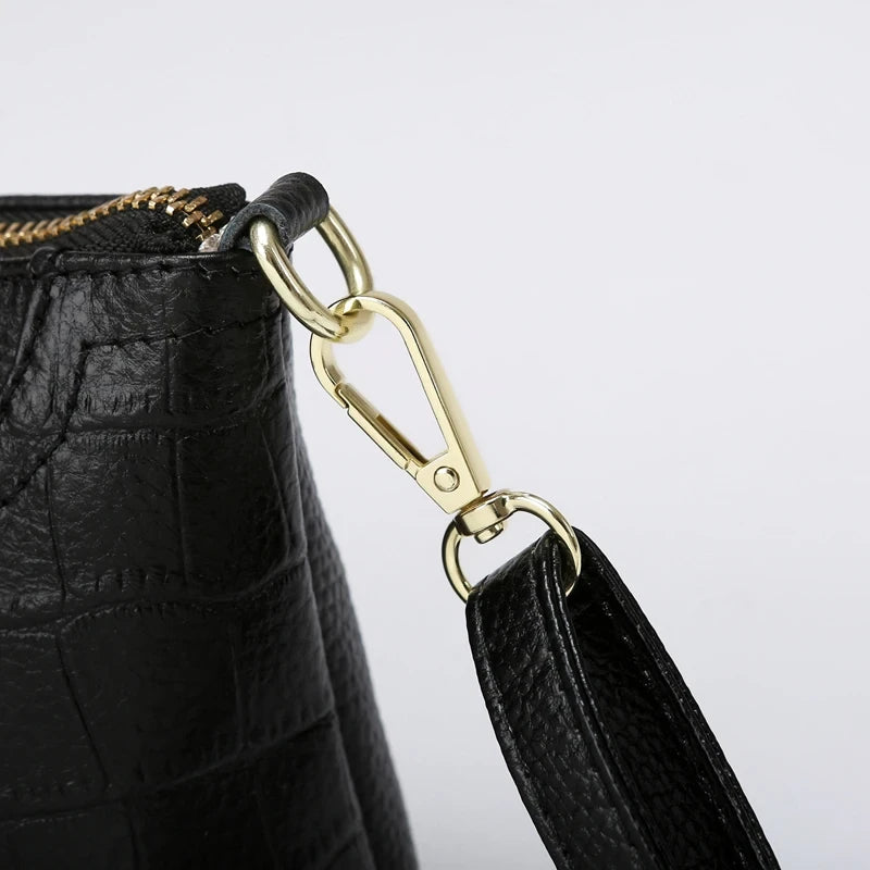 Detail of a gold clasp and black leather handle on an elegant bag.