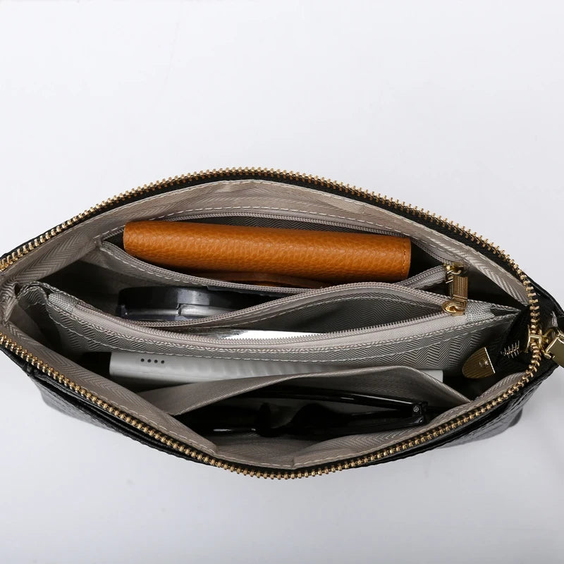Image of an open black bag, showing internal compartments organized with items such as a notebook, pen and other accessories.