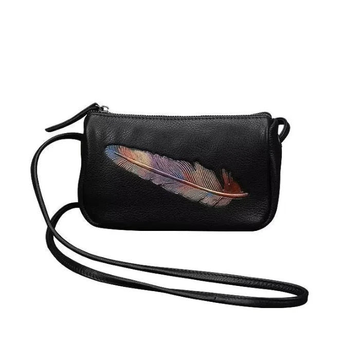 Black leather crossbody bag with colorful feather embossed detail and long strap, front view.