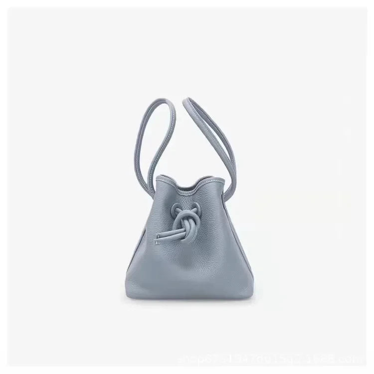 A stylish blue leather bag with a unique knot design and dual handles - front view.