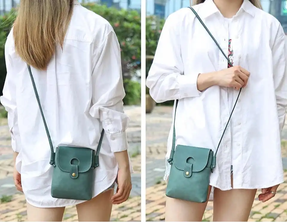 a woman wearing a loose white shirt holding a pastel blue leather crossbody bag in outdoor setting.