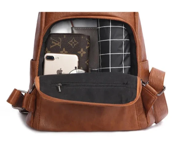 Organized storage space inside a leather backpack with various items.