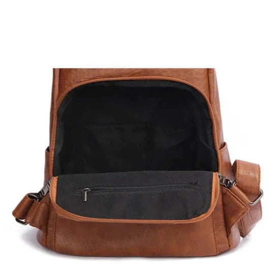 Open brown leather backpack showcasing spacious interior and interior pocket.