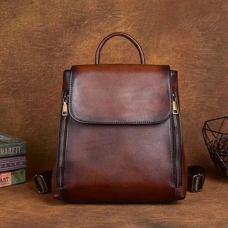 Modern brown leather bag with zippers and handle, front view.
