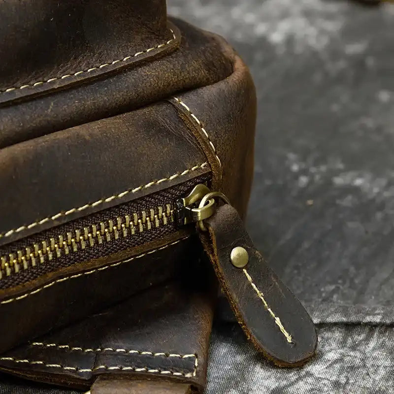 Close-up image of a brown leather bag with zipper, highlighting the crafted finish and stitching details.