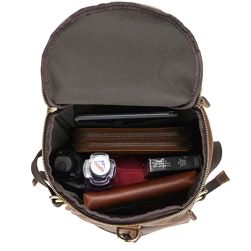 Inside view of a brown leather duffle bag, showing its organized contents, including a tablet, wallet and other useful items.