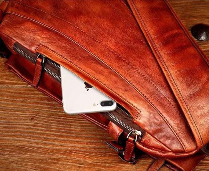 A stylish leather shoulder bag with a smartphone tucked inside a back pocket, highlighting modern functionality.