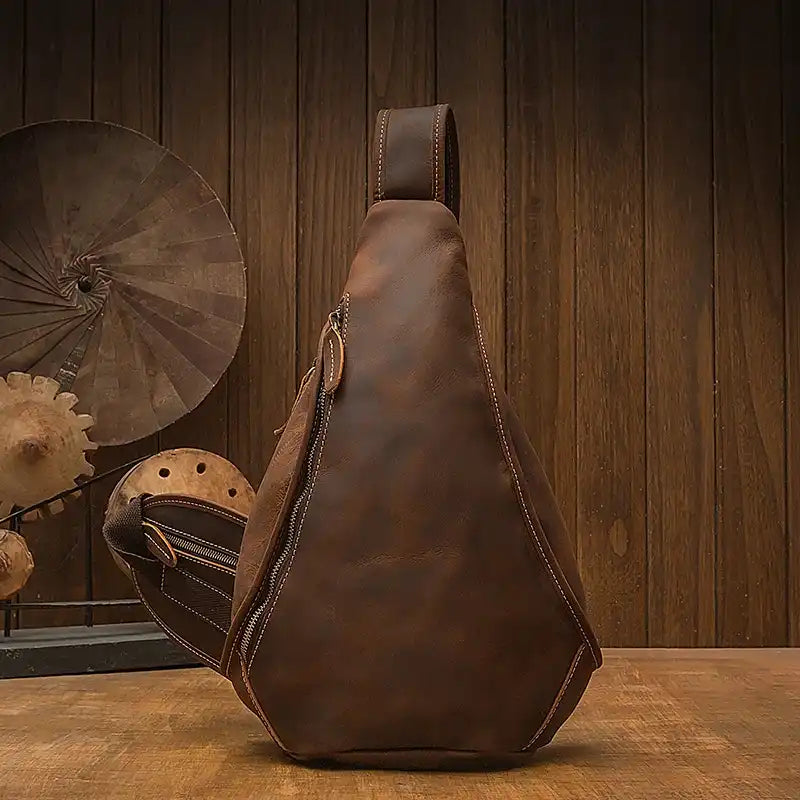 Stylish design of a brown leather sling bag with a zipper - front view.