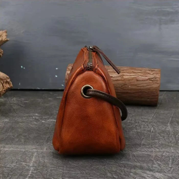 Brown leather crossbody bag with colorful feather embossed detail, side view.