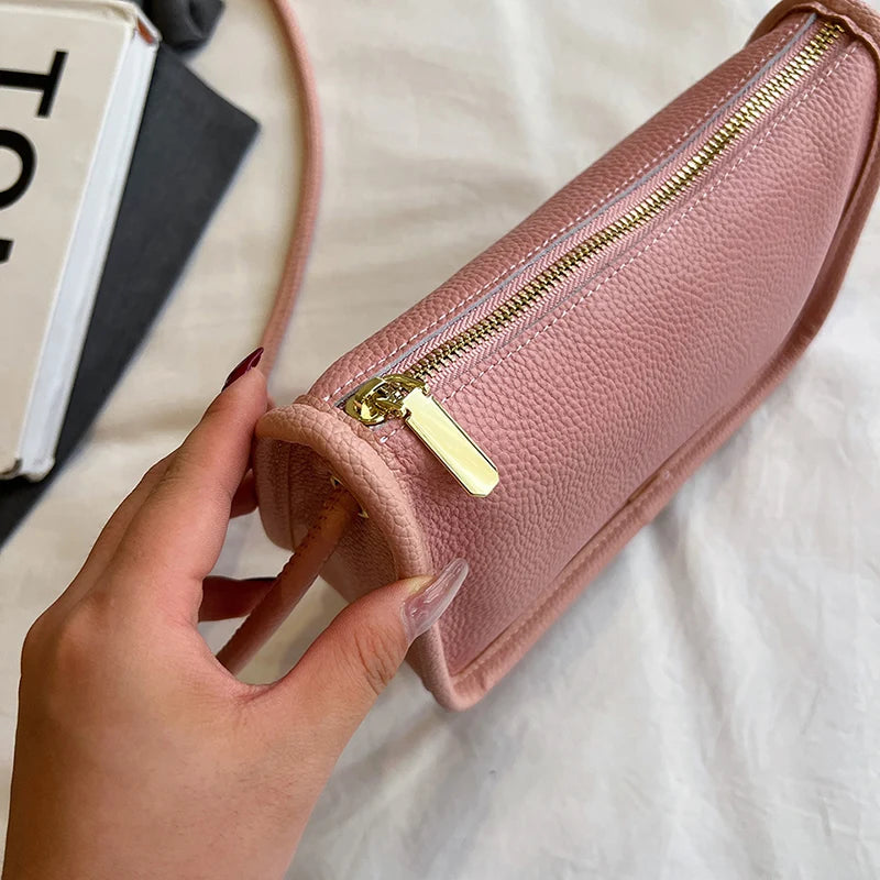 Close-up view of a pink leather crossbody showcasing its texture and zipper.