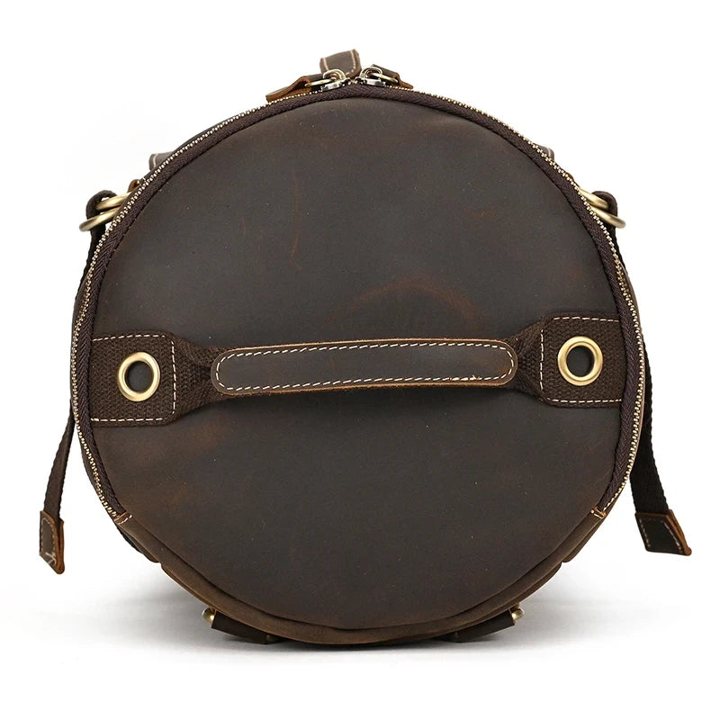 Round shaped dark brown leather duffle bag. Elegant and functional design, with handles and zipper closure, top view.