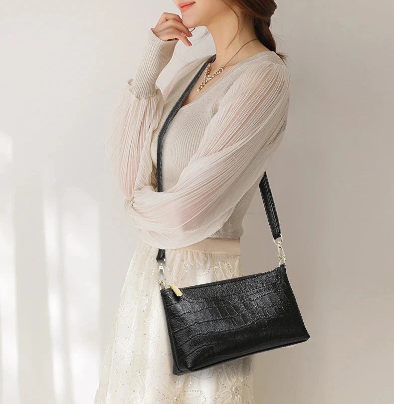 woman wearing an elegant black crocodile leather shoulder bag.