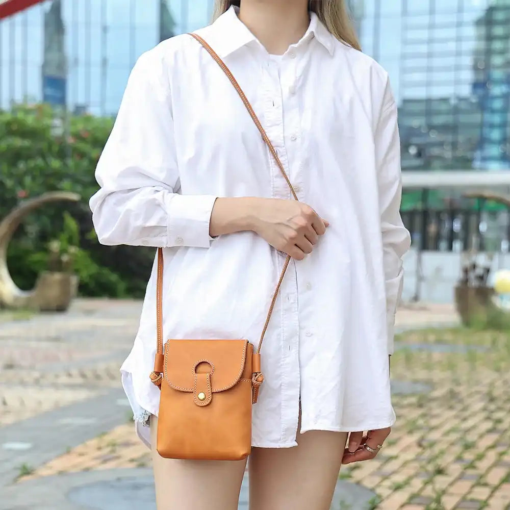 woman in white shirt wearing an elegant brown leather crossbody on the shoulder - front view