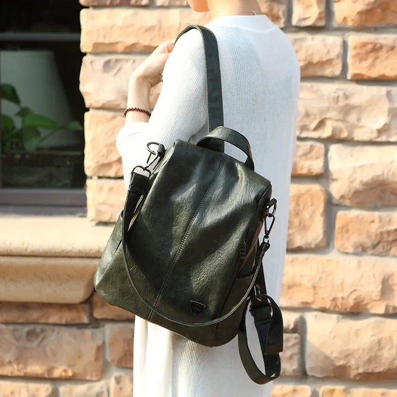 A stylish green anti-theft leather backpack carried by a woman in a casual outfit.