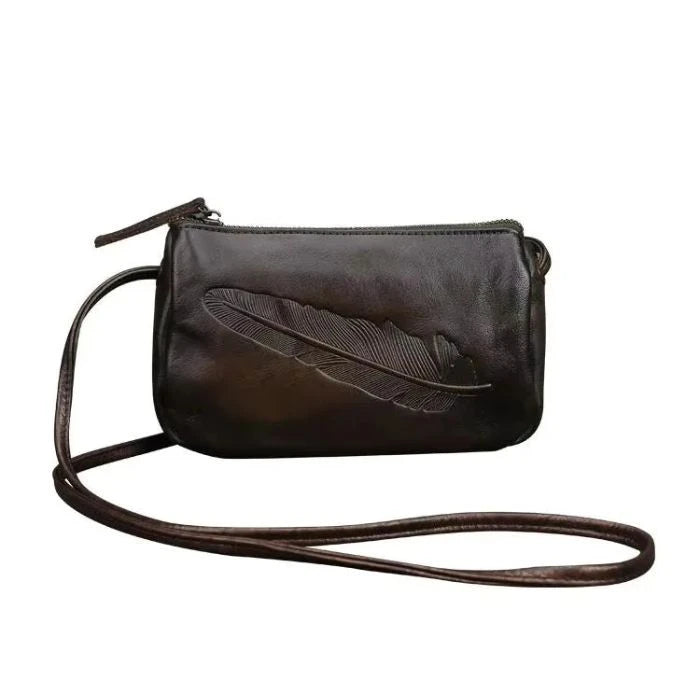Dark green leather crossbody bag with feather embossed detail and long strap, front view.