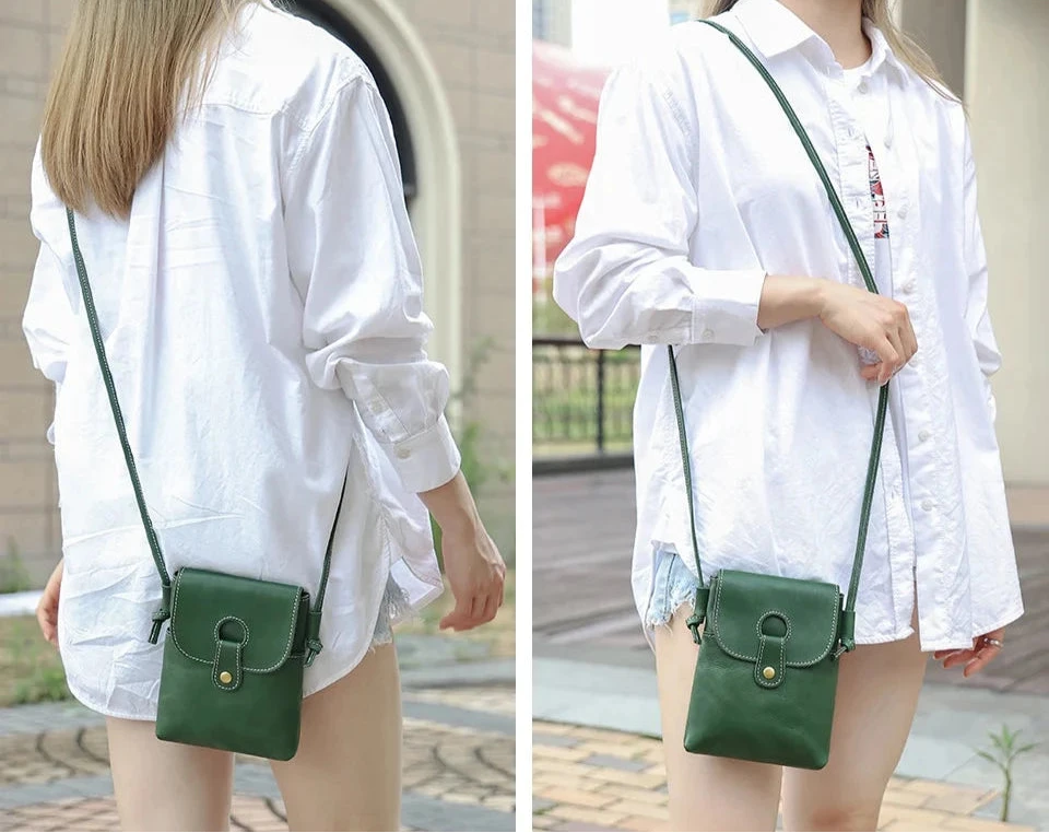 a woman wearing a loose white shirt holding a green leather crossbody bag in outdoor setting.