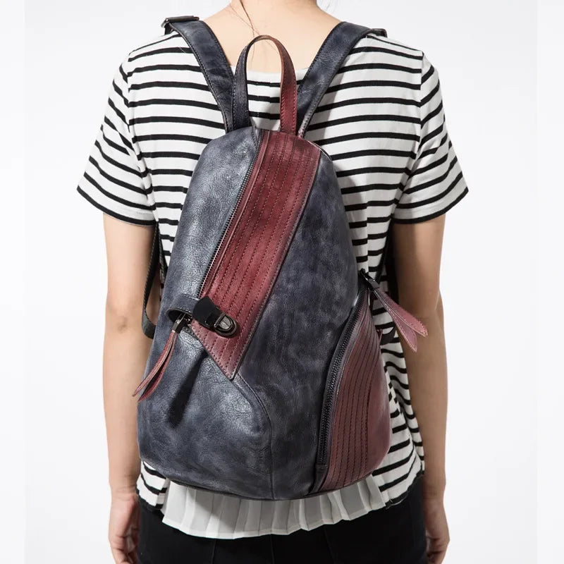A stylish leather backpack with purple and black design, worn by a person from the back.