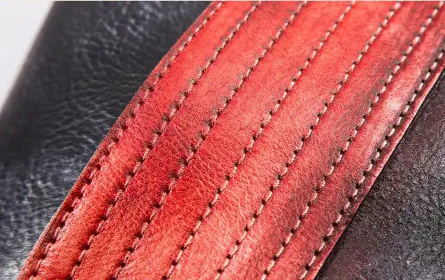 Textured surface of red and black leather showcasing craftsmanship with detailed stitching.