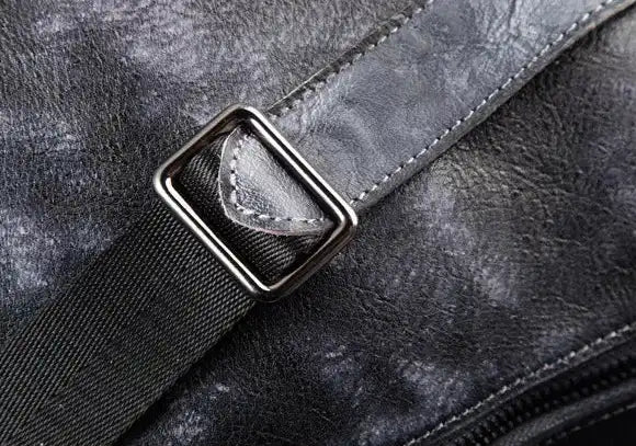 Detailed texture of a black leather bag with strap.