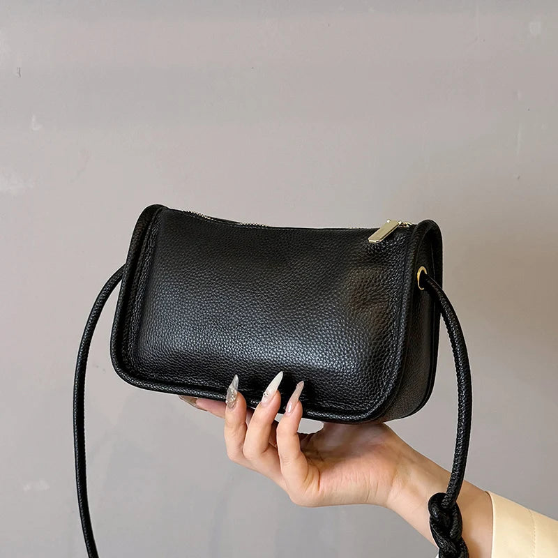 Modern black crossbody bag featuring a sleek design held in hand.