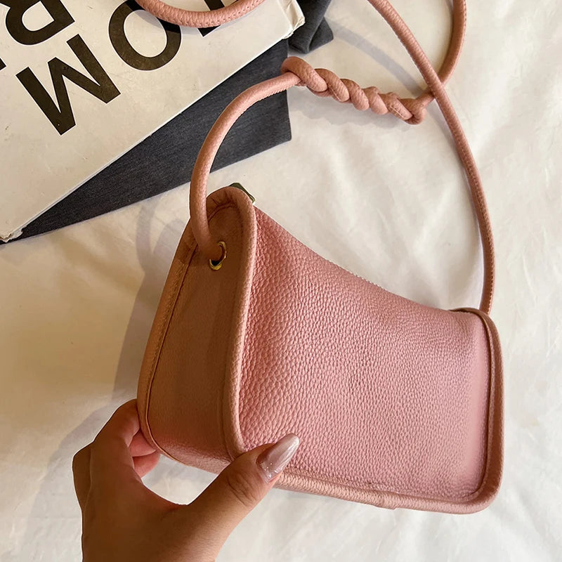Trendy pink leather crossbody bag held in hand