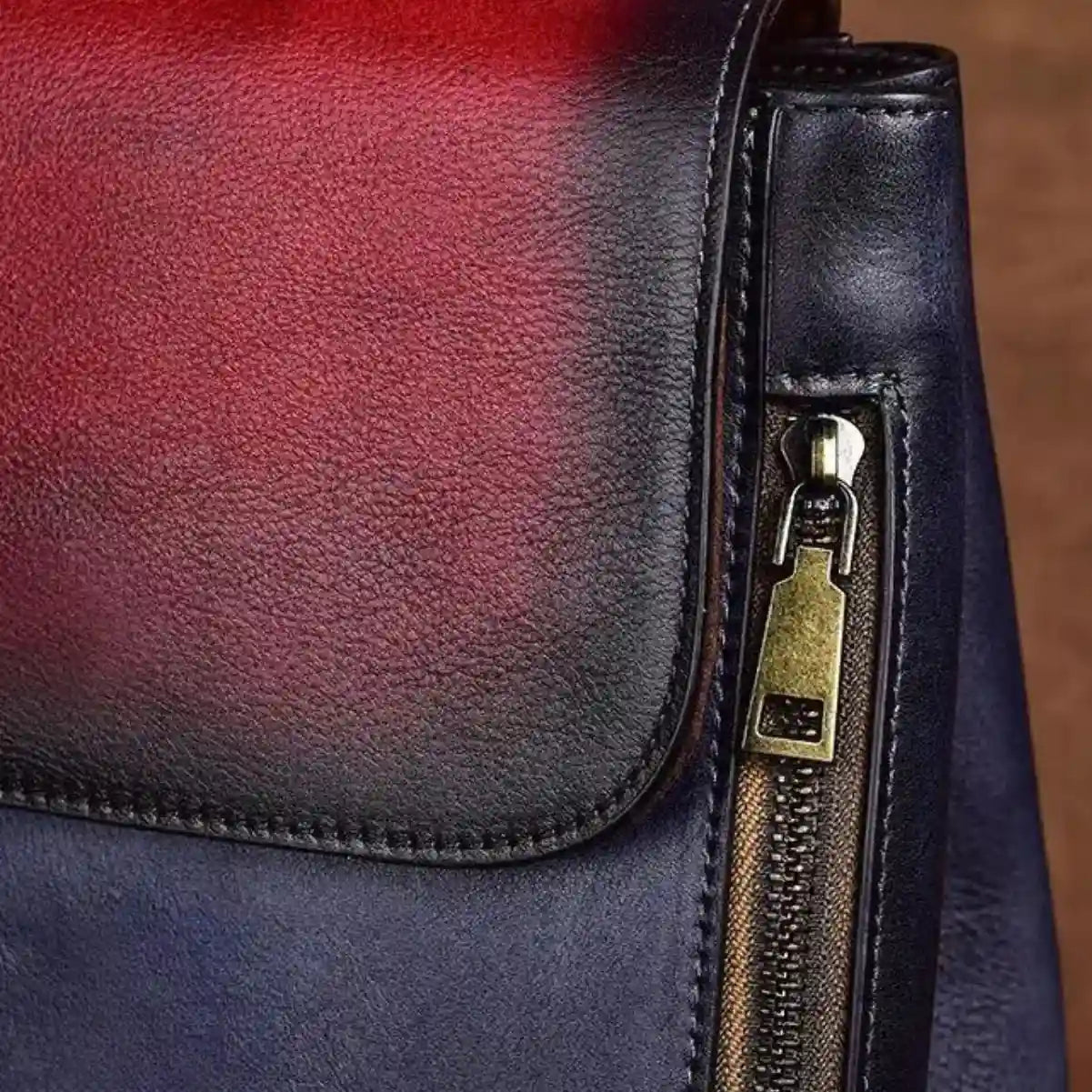 Detail of an elegant leather bag, showcasing a contemporary zipper design with red and blue tones.