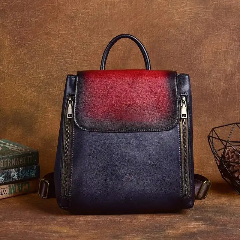 Leather backpack with an elegant design in red and blue colors, with zippers and handle, front view.