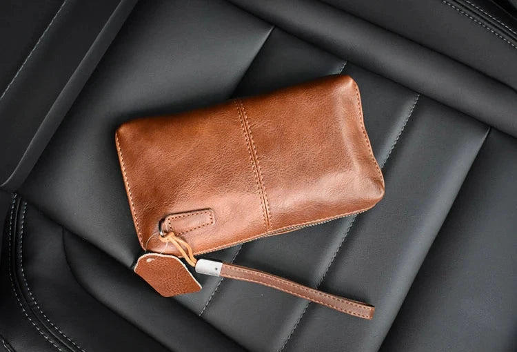 Stylish leather wallet in brown color on a black leather seat - back view.