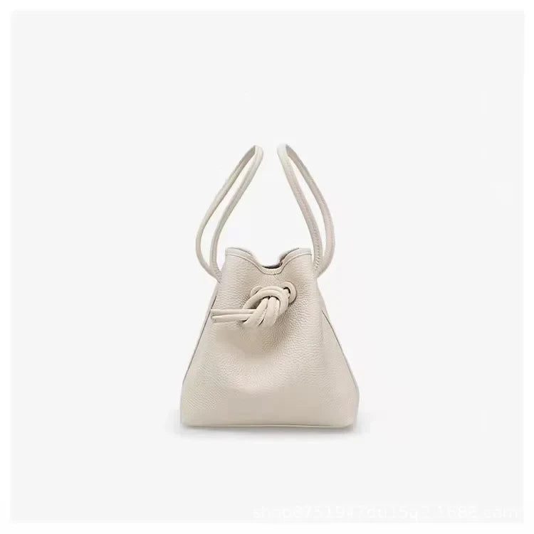A stylish white leather bag with a unique knot design and dual handles - front view.