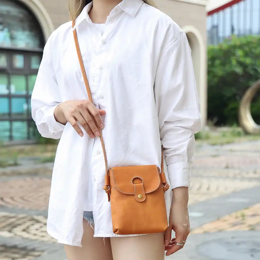 woman in white shirt wearing an elegant brown leather crossbody across the body - front view