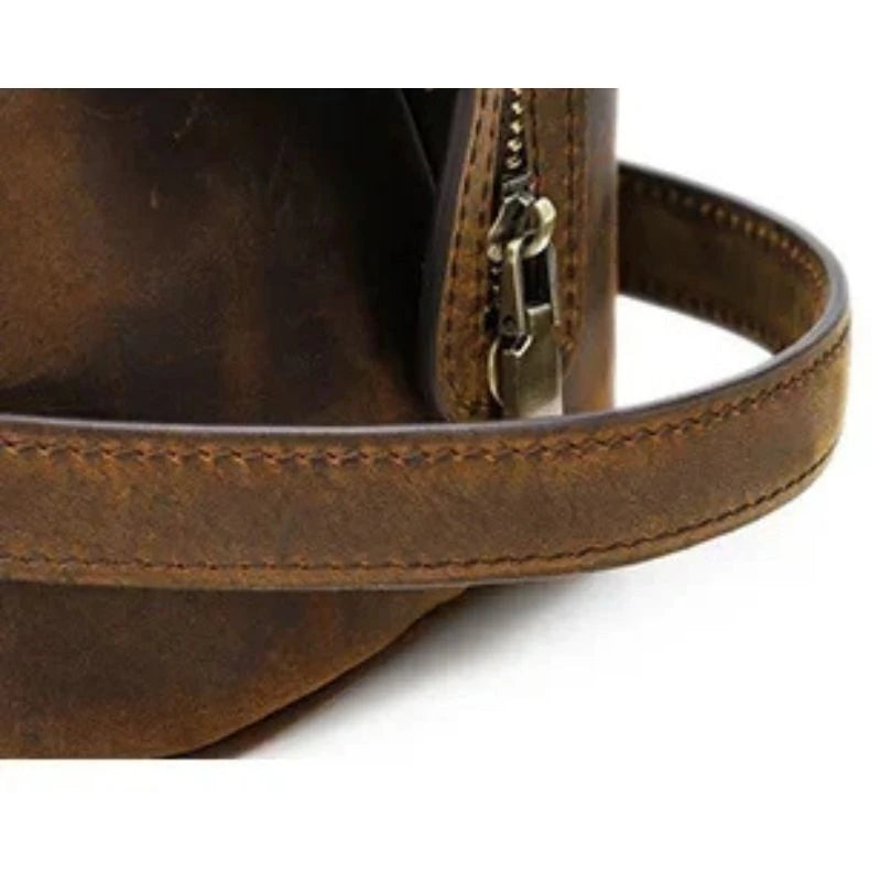 detail of a brown leather toiletry bag with zipper details, and soft handle.