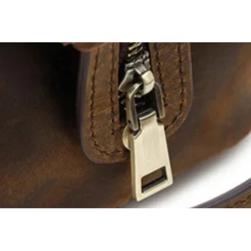Detail of a brown leather toiletry bag with zipper details.