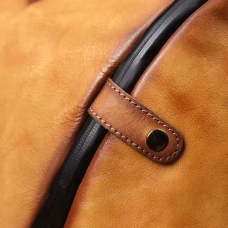 Detail view of the snap button of a brown leather bag.