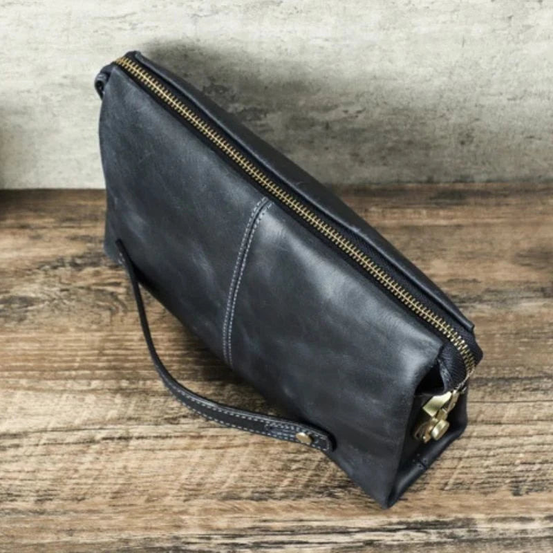 Clutch bag in durable blue leather with a zipper and handle, perfect for carrying essentials elegantly.