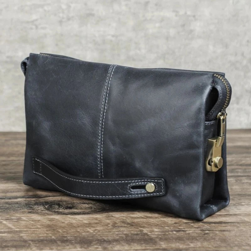 Blue clutch bag in durable leather with a zipper and handle, perfect for carrying essentials elegantly.