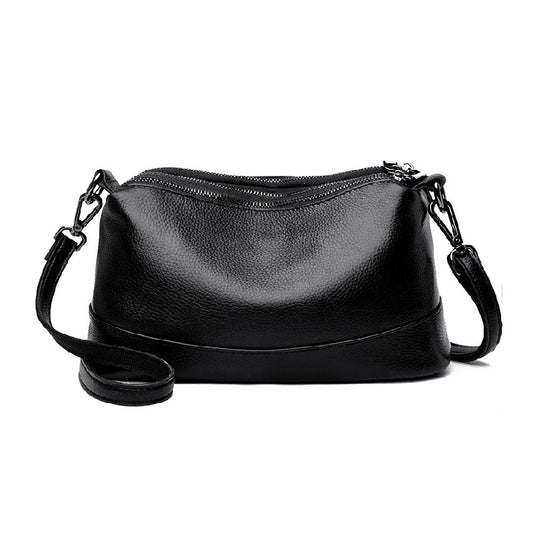 Black leather handbag with a strap on a white background, front view.