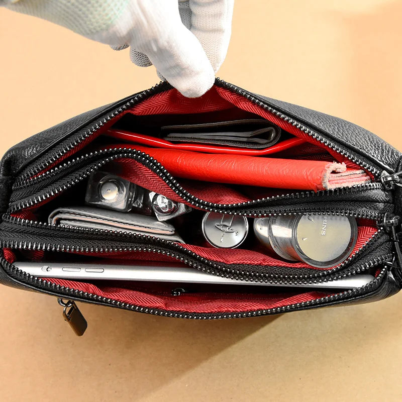 close up view with red lining and three zippered compartments.