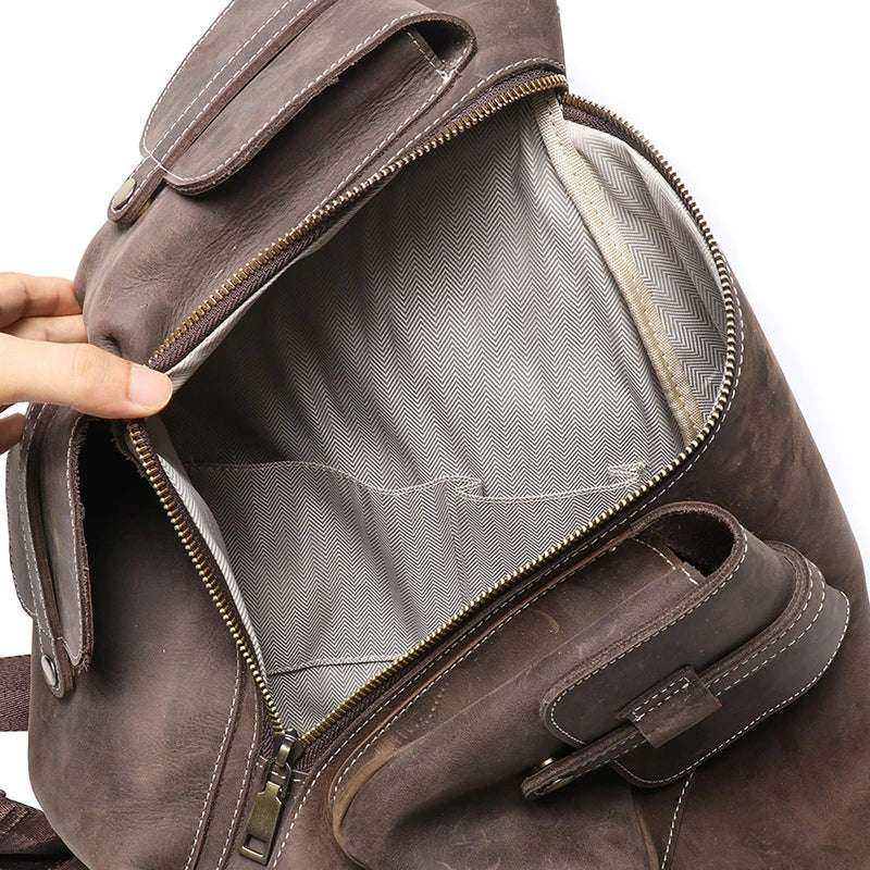 Vintage dark brown leather backpack with open main compartment, gray lining, interior pockets & durable zipper closure.