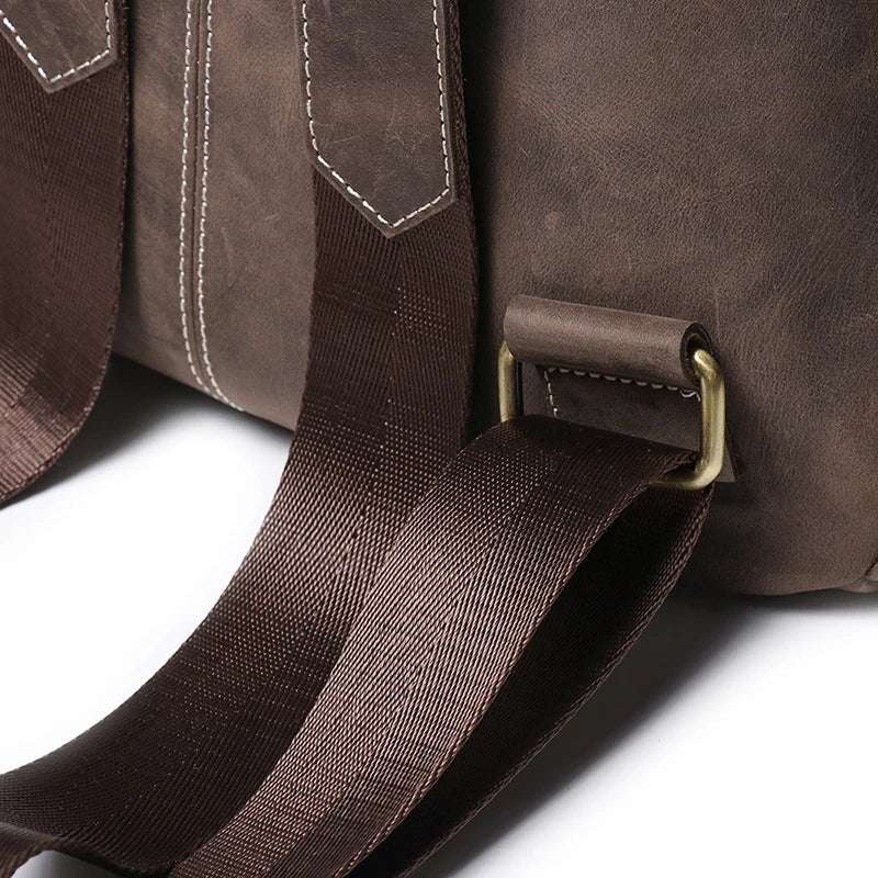 Close up featuring dark brown leather backpack white stitching, adjustable straps with brass hardware showcasing craftsmanship.