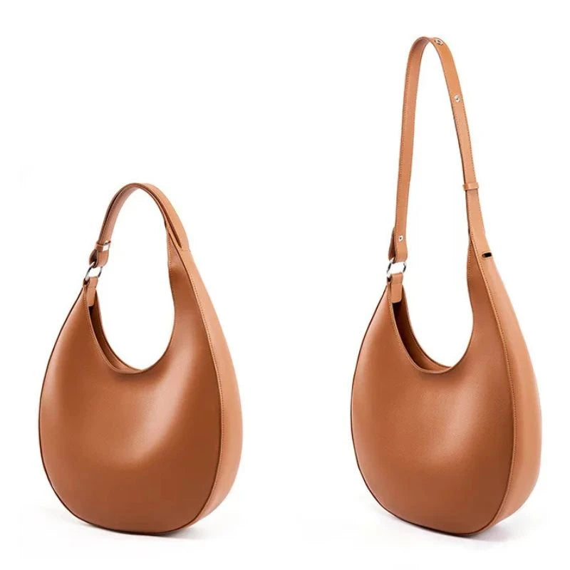 Oval-shaped brown leather bag showing strap extension.