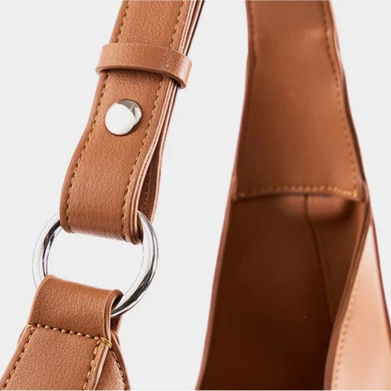 detail of a brown leather strap featuring stitching details and silver buckles.