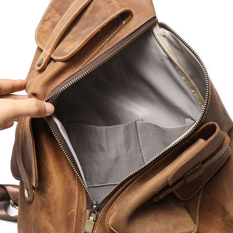 Vintage men's leather backpack with open main compartment, gray lining, interior pockets & durable zipper closure.