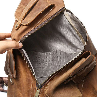 Vintage men's leather backpack with open main compartment, gray lining, interior pockets & durable zipper closure.