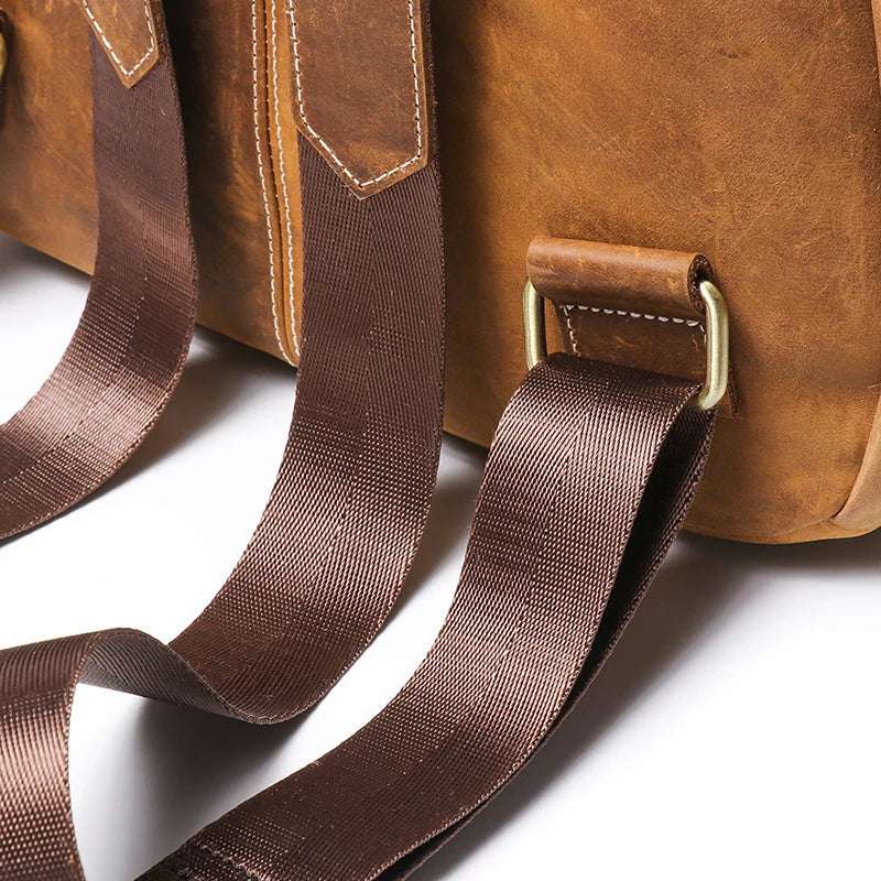 Close up featuring brown leather backpack white stitching, adjustable straps with brass hardware showcasing craftsmanship.