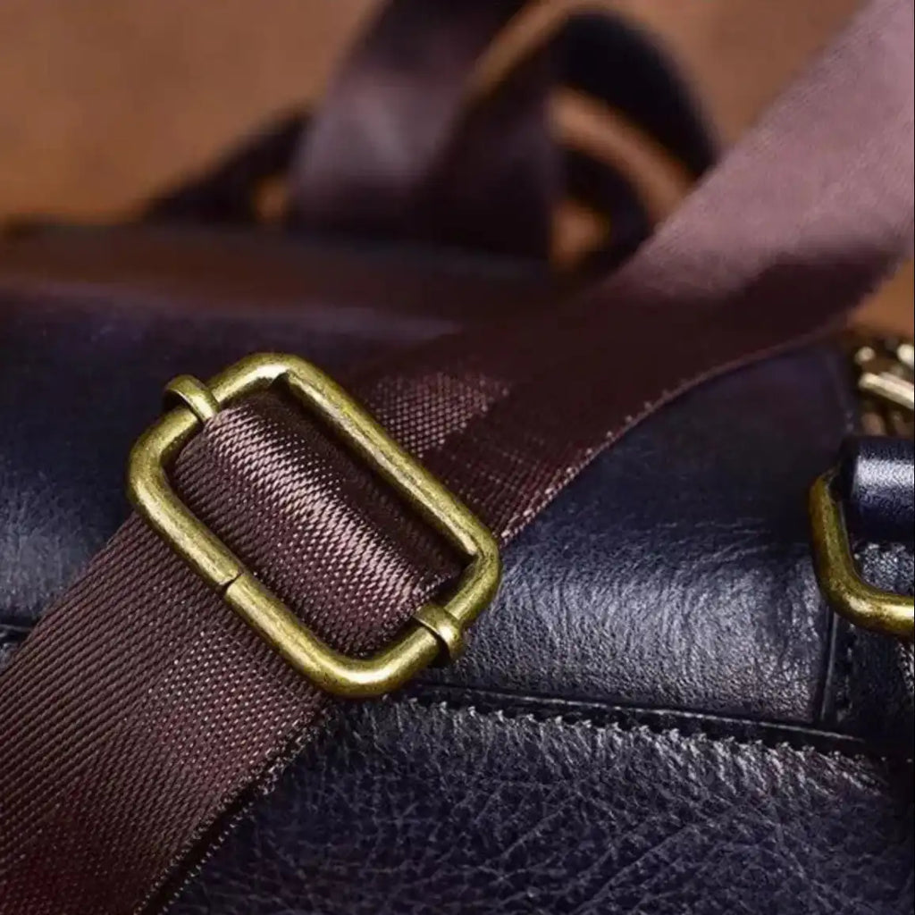 Detail of the clasp of an elegant bag with a brown fabric handle and gold metal finish.