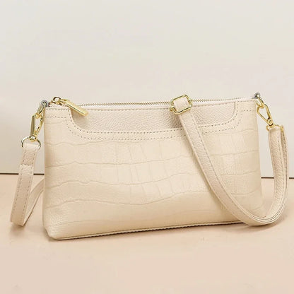 Beige crocodile leather bag with gold details, ideal for a sophisticated and elegant look. front view.