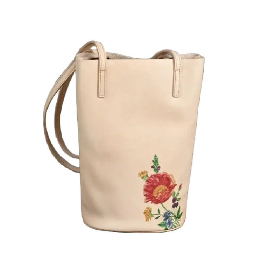 Beige bucket bag with floral print on a white background, front view.